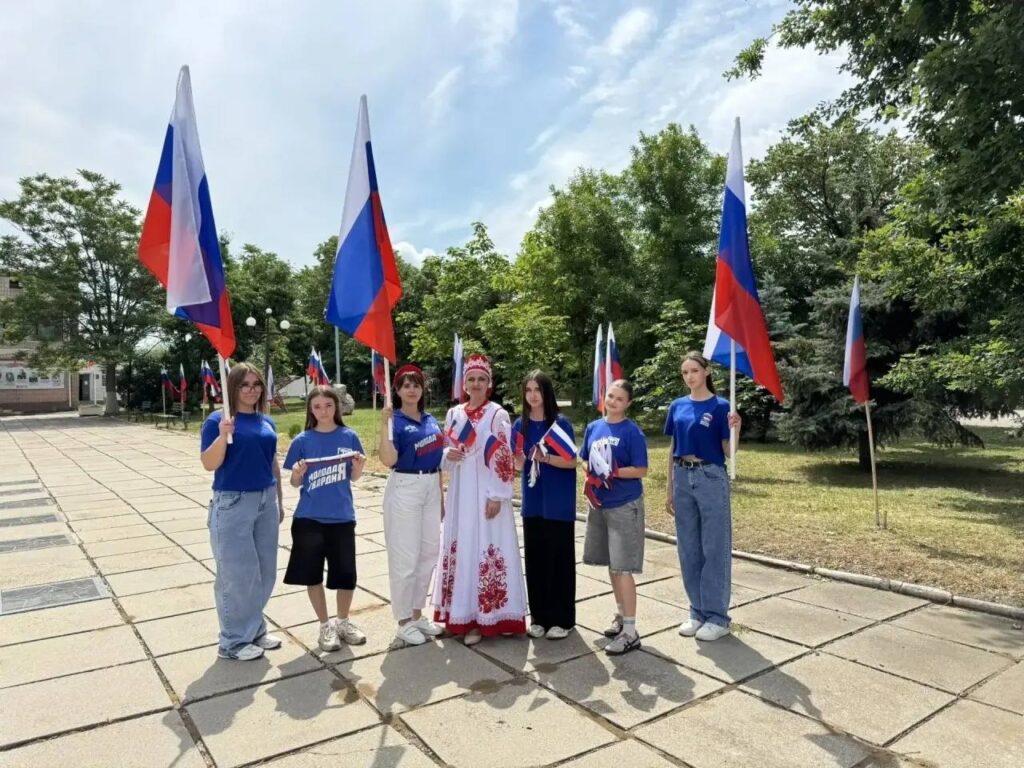 Участники «Молодой гвардии Единой России» раздают российские флажки на центральной улице посёлка Приазовское Мелитопольского района Запорожской области в рамках пропагандистской акции ко Дню России